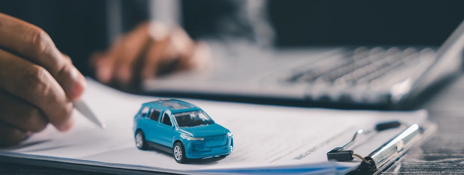 Car insurance paperwork being filled in beside a set of keys